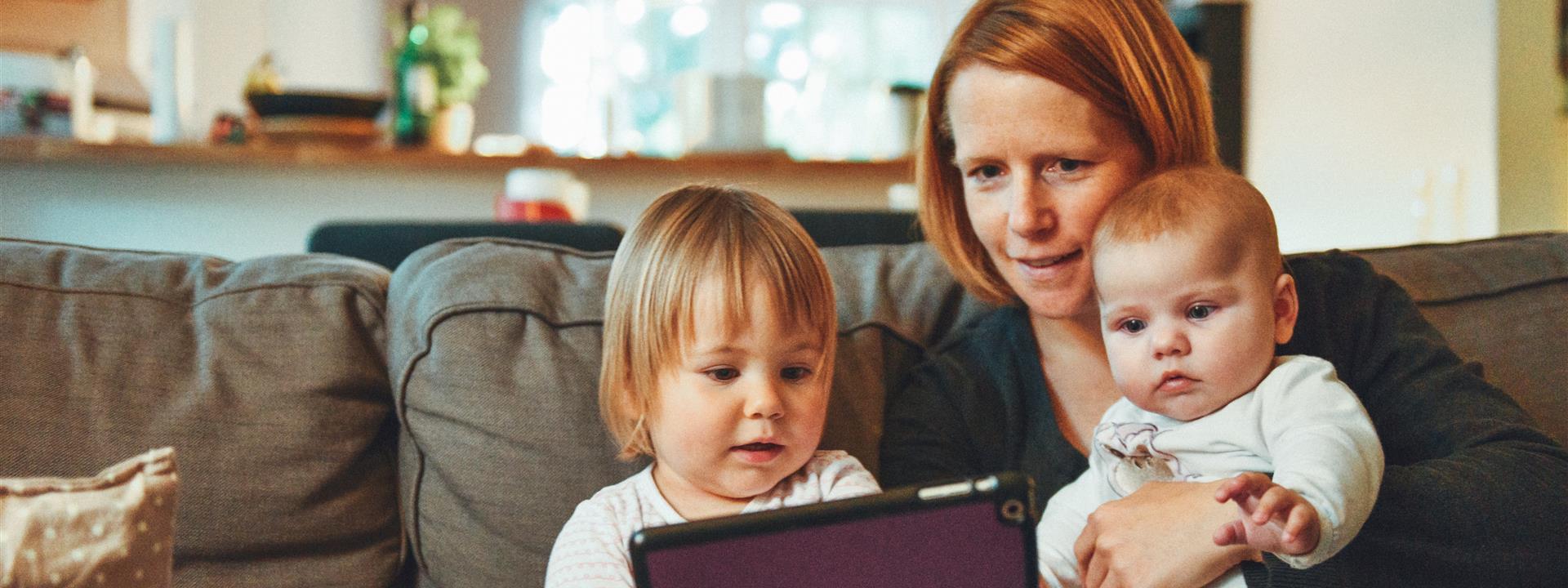 A mother with two young children looking at a tablet