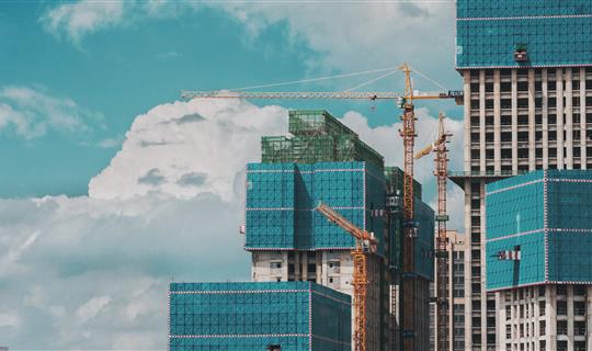 Several cranes next to tall office blocks