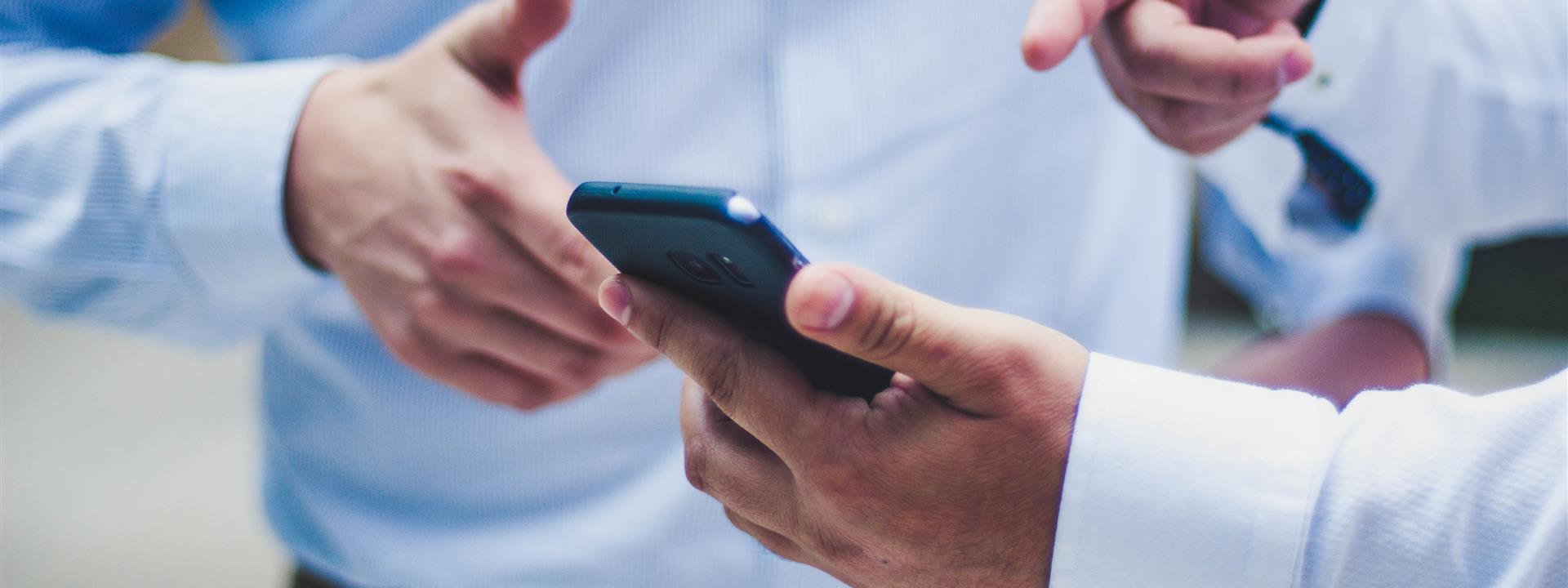 a close up of two businessmen looking at a mobile phone screen