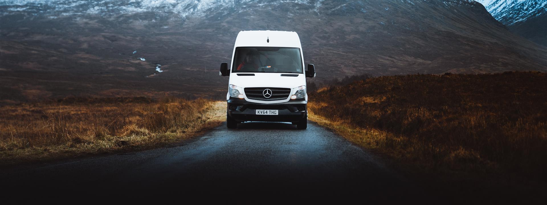 a van on a deserted road with a mountain in the background