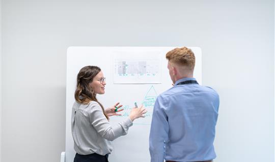 a man and woman looking at an image on a wall