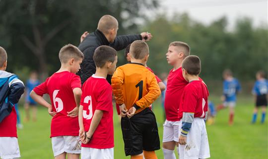 Kids playing football having prematch take with coach